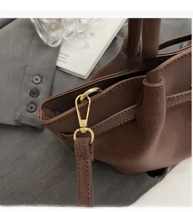 Detail of high-gloss gold hardware and premium dark brown leather on the handbag