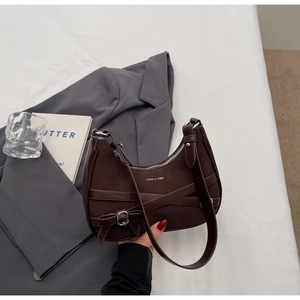 Détail du sac croissant en daim et cuir avec boucle noeud et bandoulière réglable