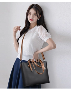 Close-up of black tote bag featuring lychee texture leather and brown shoulder strap