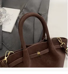 Close-up of vintage dark brown tote bag with thick handles and gold metal buckles