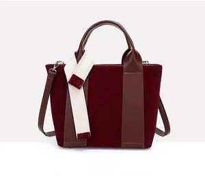 Detail view of burgundy bucket bag featuring spliced suede and smooth leather texture