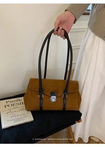 Detail of a brown suede handbag with black leather handles and silver twist lock