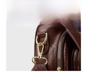 Close-up of dark brown lychee leather bag featuring polished gold metal hooks and zippers