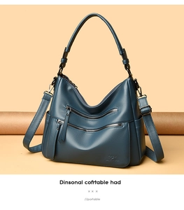 Detail of dark teal pebble leather bag with dual zipper pockets and kangaroo logo