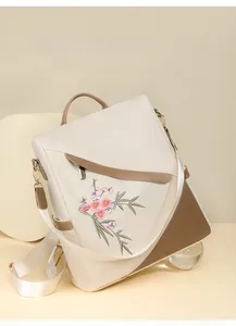 Detail of floral embroidery on cream waterproof nylon backpack with brown accents