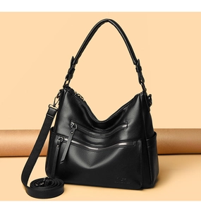 Detail view of black pebble leather handbag with triple front zipper pockets and strap