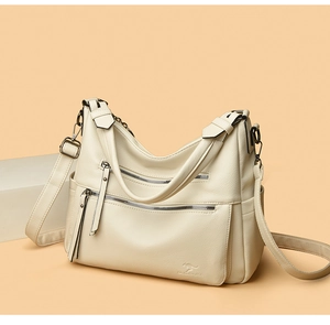 Detail of off-white lychee grain leather handbag featuring multi-zipper layers and logo