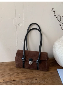 Detail of retro suede baguette bag with metal buckle on vintage wooden surface