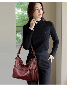 Detail of wine red pebbled leather shoulder bag with functional metal zippers and pockets