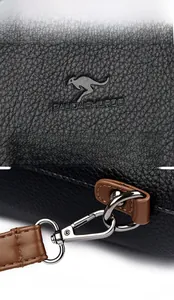 Detail of embossed logo and silver metal buckle on black lychee leather tote bag