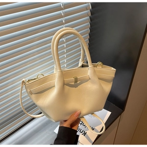 Close-up of cream wing-shaped tote bag showing matte texture and gold clasp detail