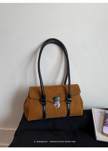 Macro detail of brown suede handbag with black leather straps and silver metal clasp