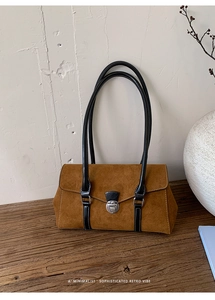 Detailed view of caramel suede shoulder bag with black leather straps and silver buckle