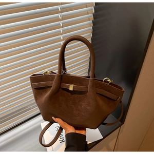 Detail of dark brown pebble leather handbag with gold metal clasp and pleated side design