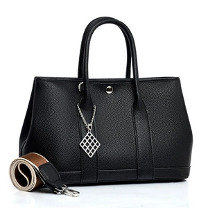 Black pebble leather tote bag with silver charm and removable striped fabric strap