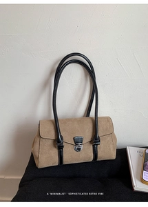 Detail of retro suede shoulder bag with black leather trim and silver metal buckle