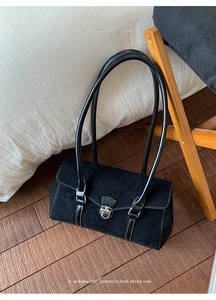 Macro view of retro black suede tote bag with silver buckle and minimalist handle detail