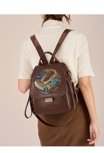 Detailed close-up of dark brown leather backpack with colorful elephant relief pattern