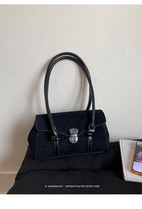 Detail of retro black suede shoulder bag featuring a silver clasp and leather handle