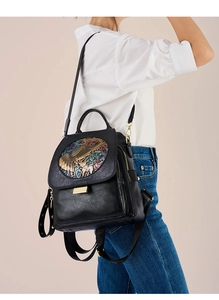 Detail of retro relief metal ornament with mythical beast motif on black leather backpack