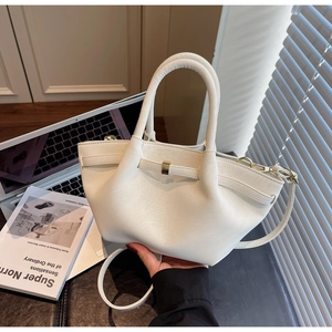 Close-up of cream matte leather wing bag featuring a gold rectangular metal buckle detail