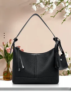 Close-up of black woven texture handbag with detachable mini pouch on pink background