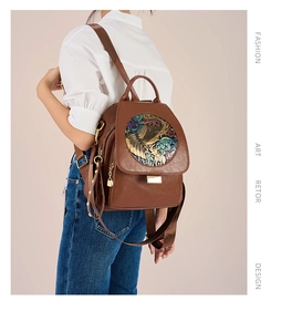 Detail of dark brown leather backpack with retro relief ornament and metal clasp