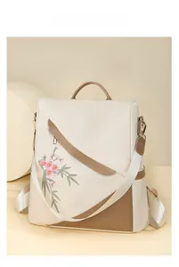 Detail of cream and brown backpack featuring delicate pink floral embroidery and top handle