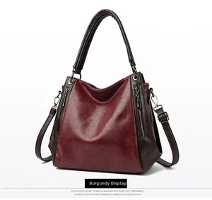 Close-up of vintage burgundy leather tote bag with dual zipper detail and rounded handles