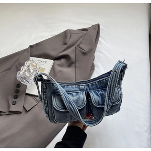 Detailed macro of vintage washed denim underarm bag with flap pockets and silver rivets