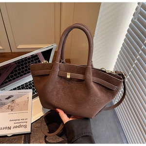 Detailed view of coffee brown retro textured wings bag with pleated sides and gold hardware