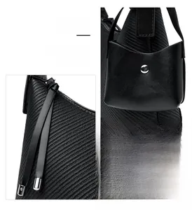 Detail of black woven shoulder bag featuring long leather zipper pulls and mini pouch accessory