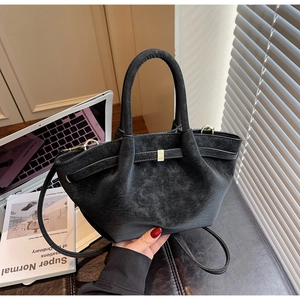 Close-up of black matte handbag with gold buckle and adjustable strap in office setting
