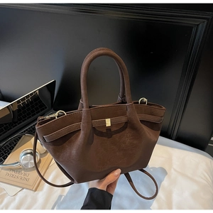Detailed view of dark brown matte leather wing bag with pleats and gold metal hardware