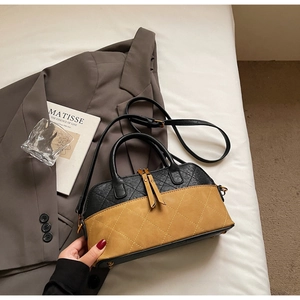 Détail de la texture en cuir matelassé et de la fermeture à franges sur le sac bicolore