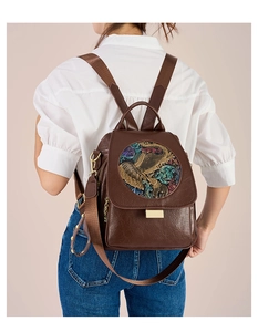 Detail of vintage brown backpack with ethnic elephant relief patch and gold metal locks
