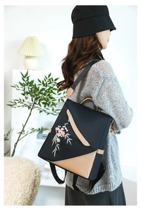 Detail of floral embroidery and leather trim on a stylish large black backpack