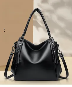 Detail of black lychee grain tote bag with silver zippers and elegant tassel charms