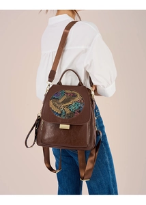 Detail of dark brown leather backpack with vintage elephant relief and gold buckle