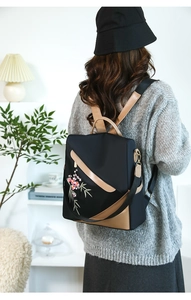 Detail of waterproof nylon backpack featuring floral embroidery and leather accents