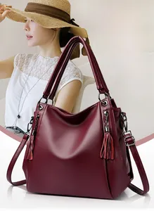 Detail shot of the burgundy textured leather tote bag with stylish fringe tassel pendant