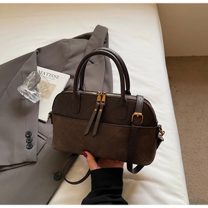 Detail of dark brown quilted shell bag with matte texture and vintage gold hardware