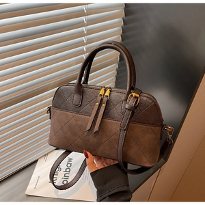 Close-up of vintage brown shell bag with quilted stitching and gold hardware detail