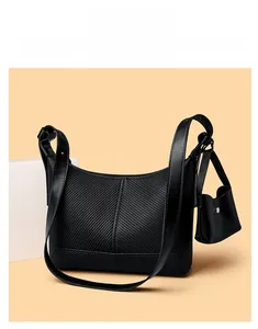 Detail of black faux leather baguette bag with herringbone texture and mini pouch