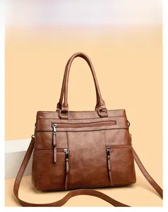Detail of brown faux leather tote bag with functional zippers and litchi texture