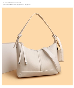 Detail of beige baguette bag with woven texture, shoulder strap and mini pouch