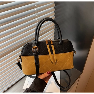 Detail of quilted mustard yellow and black shell bag with matte texture and gold zipper