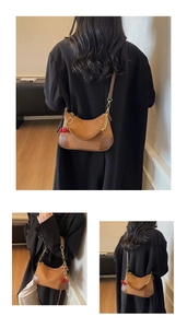 Detail of brown vintage underarm bag with gold chain and red cherry pendant accessory