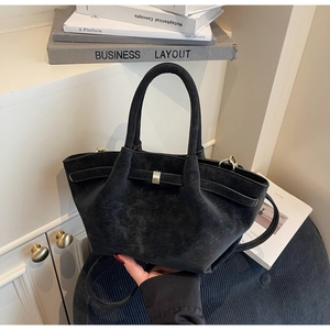 Close-up of black matte trapezoid handbag with retro wing design and metal buckle detail