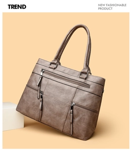 Detail of vintage brown tote bag showing pebbled faux leather texture and zip pockets